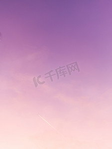 华丽的粉红色、珊瑚色和紫色日落，云彩和飞行的飞机。