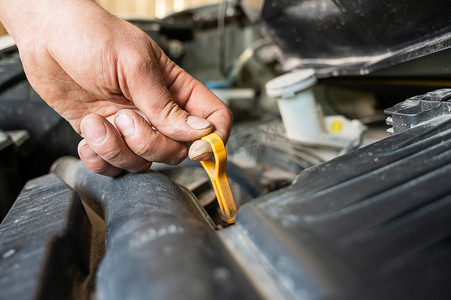 汽车修理工拉出量油尺检查汽车发动机中的油位。