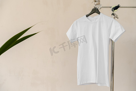 纯白色棉质 T 恤挂在衣架上，适合您的设计