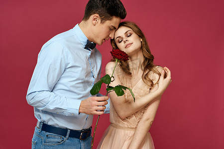 浪漫情侣的肖像，爱上孤立背景中的红玫瑰和经典西装晚礼服