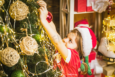 可爱的小女孩正在装饰圣诞树。