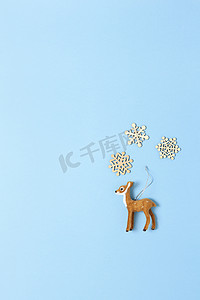 圣诞装饰、自然主义玩具狍子和淡蓝色背景上的三片小木雪花，复制空间。