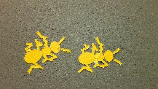 蚂蚁工作摄影照片_灰色的墙上画着黄色的蚂蚁。