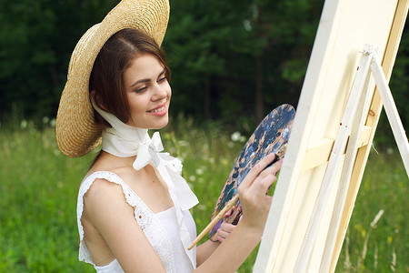 穿着白色连衣裙的女人在户外艺术家画画架