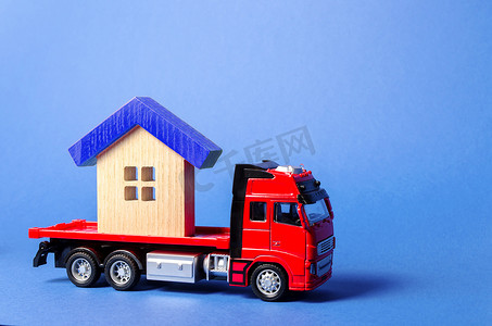 红色卡车运输车运送一座蓝色屋顶的房子。