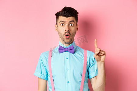有创意的男人提出一个想法，用举起的手指说建议，站在粉红色的背景上