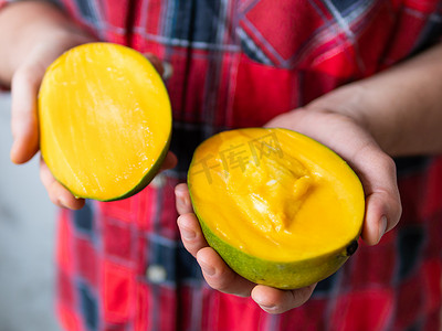 身穿格子呢格子衬衫的男人拿着 Mangifera indica，俗称芒果。