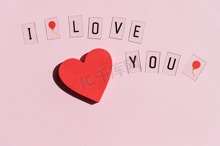 我爱你写在粉红色背景和红心上的文字。情人节快乐。