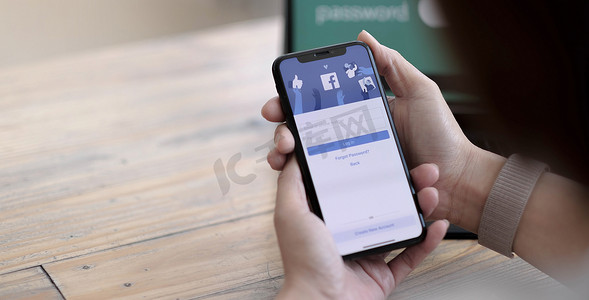 2021年8月24日，泰国清迈：一位女士拿着iPhone X，屏幕上显示社交互联网服务Facebook。