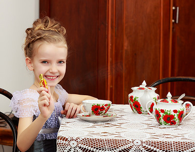 可爱的小女孩在旧桌子上喝茶。