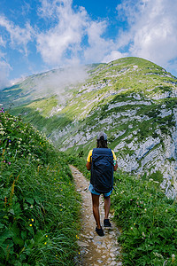 一个背着背包的女人站在山顶上，女孩前往美丽的地方，到达目标，萨克斯吕克的山脊，瑞士阿尔普斯坦阿彭策尔内罗登州的克罗伊茨贝格