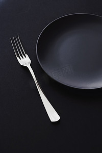 高级黑色背景摄影照片_黑色背景中的空盘子和银器、假日晚餐的高级餐具、简约的设计和饮食