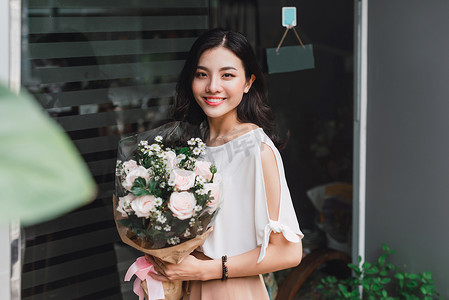 亚洲女人站在花店里拿着花束