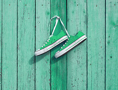 一双挂在墙上钉子上的绿色纺织运动鞋