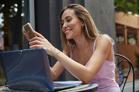 手机夏季夏季摄影照片_咖啡馆外的亚洲漂亮女孩用手机上网，在线聊天