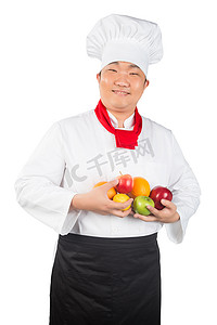 戴着围裙的男人摄影照片_戴着厨师帽的男人拿着水果