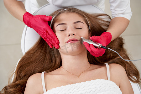 美容师对美丽的年轻患者的脸部进行硬件清洁。