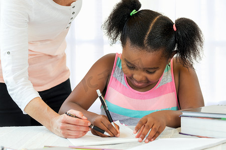 白人老师帮助黑人小女孩做数学题。