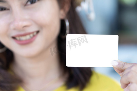 特写女性展示空的白色信用卡，面带微笑