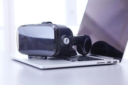 办公创新摄影照片_办公桌上配有笔记本电脑的虚拟现实护目镜。