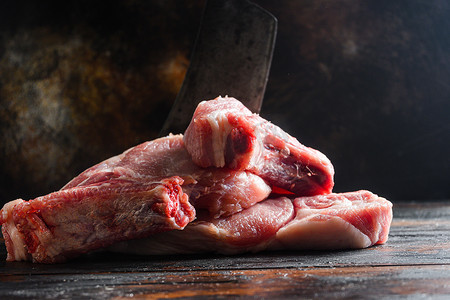 农场新鲜的猪肚，生猪肉在质朴的背景下紧贴在深色木板上，还有切肉刀，侧视