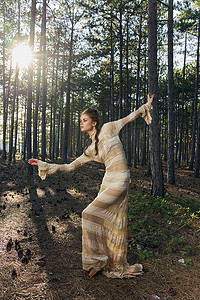 针叶林中一位穿着裙子的浪漫女人正在地上和掉落的锥体上跳舞