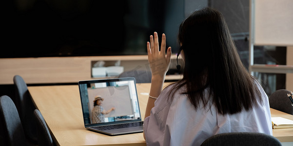 远程会议虚拟摄影照片_由于新冠疫情，亚洲年轻女学生通过远程会议向学校老师学习虚拟互联网在线课程。