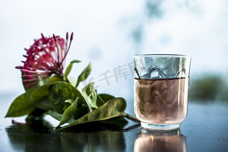 在透明玻璃碗中关闭木质表面的红色五角花或埃及星花或茉莉花，其提取的水。