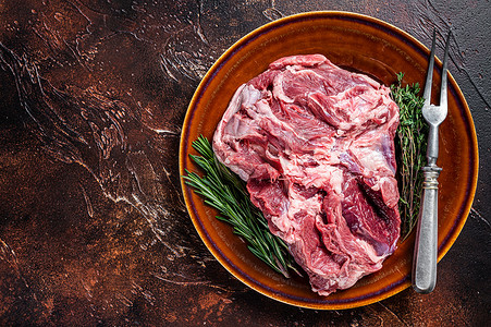 羊腿肉摄影照片_生无骨羊腿肉放在质朴的盘子里，配百里香。