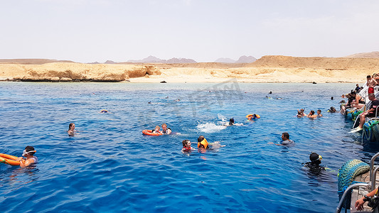 埃及，沙姆沙伊赫 — 2019年9月20日：一群戴着面罩和通气管潜水的游客正在船附近的红海中观赏美丽多彩的海鱼和珊瑚礁。