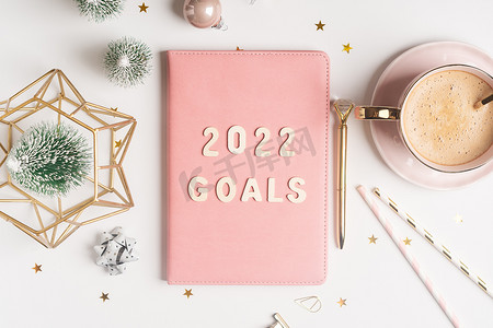 顶视图桌面圣诞粉色记事本，上面写着 2021 年目标字母文本。