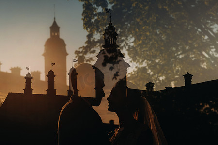 婚礼背景婚纱照摄影照片_涅斯维日城堡背景下日落时一对相爱情侣的剪影