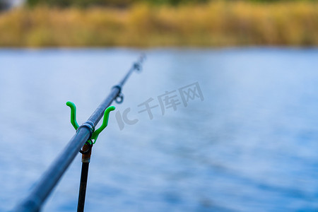 河背景上有响铃的钓鱼竿。