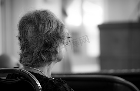 焦虑至极摄影照片_老妇人的背影坐在椅子上。