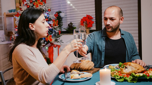 碰杯香槟摄影照片_节日晚餐上，男人和女人碰杯香槟