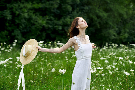 连衣裙帽子摄影照片_穿着白色连衣裙帽子的女人自然田野花