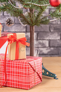 红色家背景图摄影照片_装饰圣诞树，家里包裹着美丽的红白礼物，黑砖墙，节日设计理念，特写。