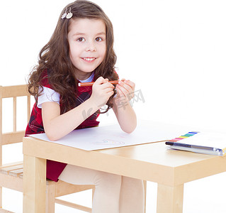 彩色铅笔创意艺术摄影照片_小女孩坐在桌边用彩色铅笔画画