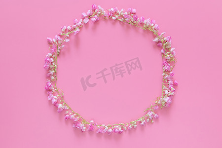 平躺的花冠，由粉红色背景上孤立的粉红色花朵制成的花环圈，顶视图。