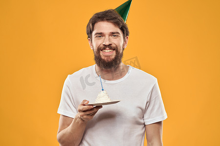 英文版生日快乐摄影照片_留着胡子、戴着帽子庆祝生日聚会黄色背景的帅哥