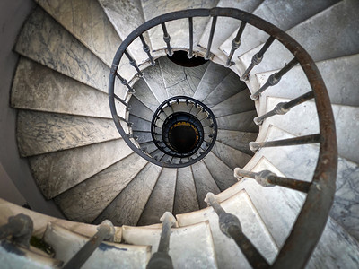 锻造摄影照片_罗马一座古老宫殿内的古老螺旋楼梯，装饰有锻铁扶手和大理石台阶。