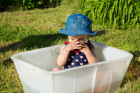 巴拿马一岁半婴儿穿着泳衣闭着眼睛坐在浴缸里