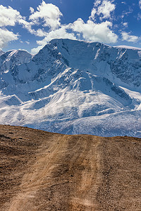 通往北楚伊斯基山脉雪山的一条高原道路的肖像尺寸景观。