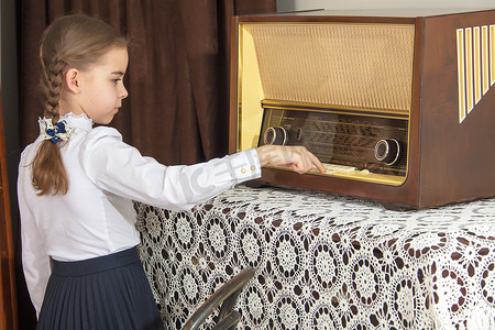 小女孩听旧收音机。