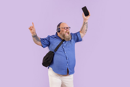 带耳机的大号男子喜欢紫色背景的手机音乐