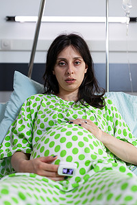 坐在医院病床上的疲惫孕妇肖像