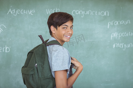教室里背着背包站在黑板上的小学生肖像