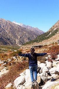 单身女性印度旅行者的后视图在冬季休闲时独自站立，双臂张开在偏远的山谷中。