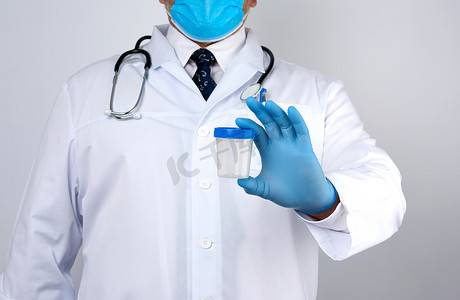 一件白色外套和领带的男性医生站立并且拿着一个空的pla