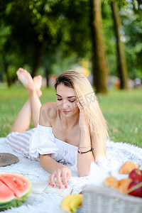 绿色阅读摄影照片_年轻女子躺在公园的格子上看书。